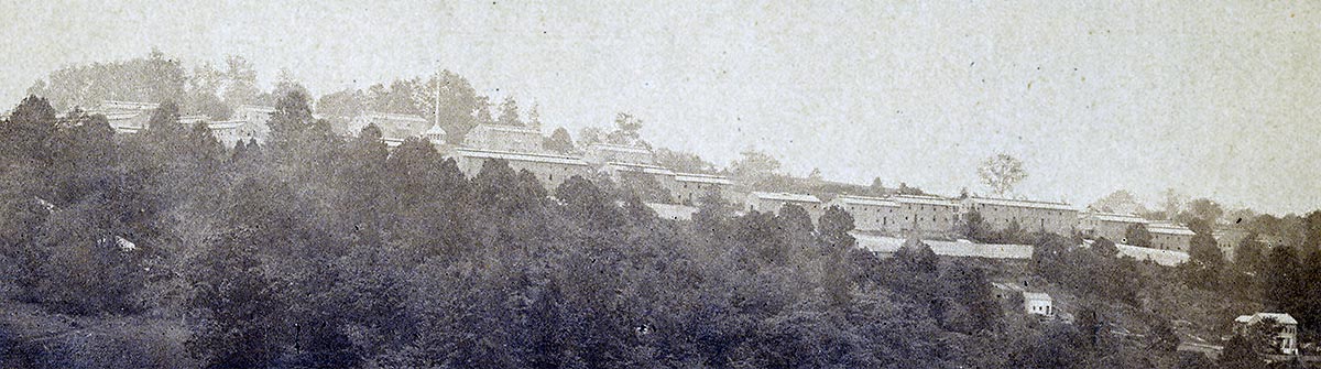 detail of the larger image: the camp buildings on the hillside above the woods