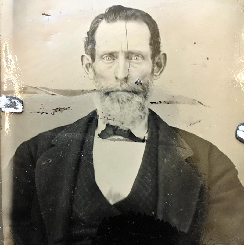 damaged photograph of middle-aged man, bearded, haunted look in his eyes