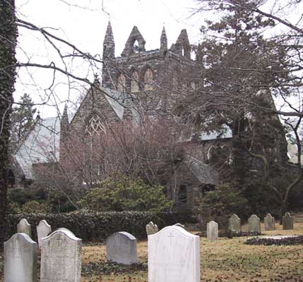 grave stones with church in background through trees
