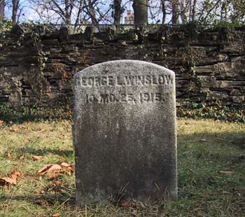 simple stone of George L. Winslow 2-3 feet tall, stone wall behind