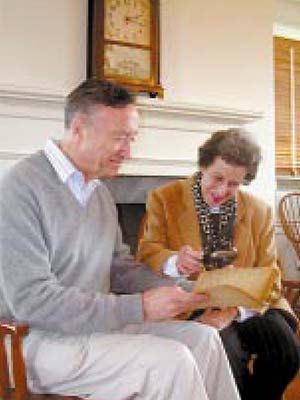 A man and woman examine a manuscript using a magnifying glass