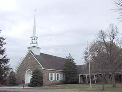 gray stone church with tall white steeple against a gray sky
