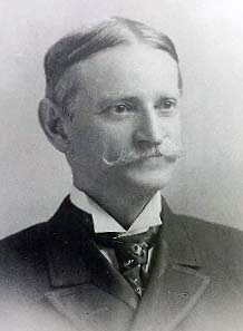 head and shoulders portrait of middle age man with full mustache, in stiff collar and cravat