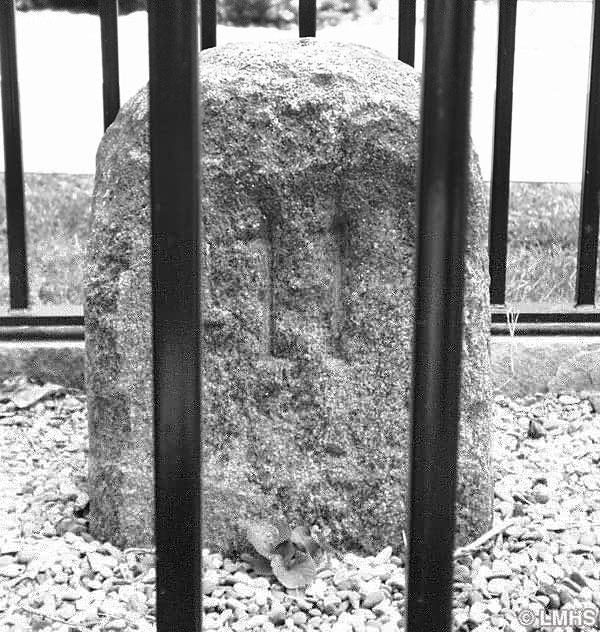 round-top stone carved with number 11, surrounded by iron fence