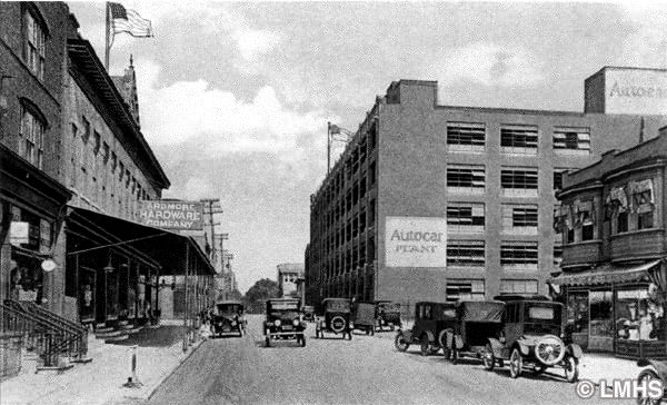 looking up a streetscape with four and five-story buildings and early automobiles