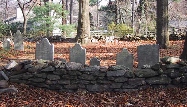 cemetery view; enclosed by a low, piled stone wall, 6 gravestones visible