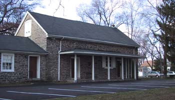 The meeting house, a plain stone building with wooden covered porch