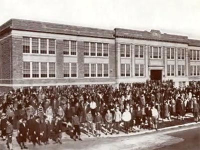 large group poses in front of  school building