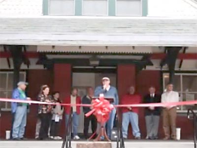 giving a speech on the station porch, group standing behind a ribbon