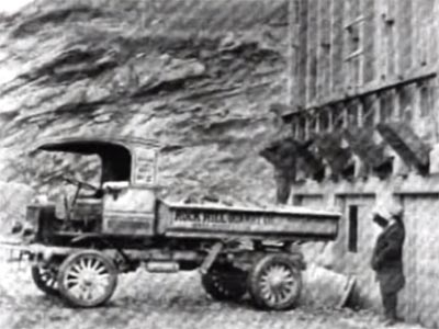 dump truck with 'Rock Hill Quarry' written on side in front of a rock cliff