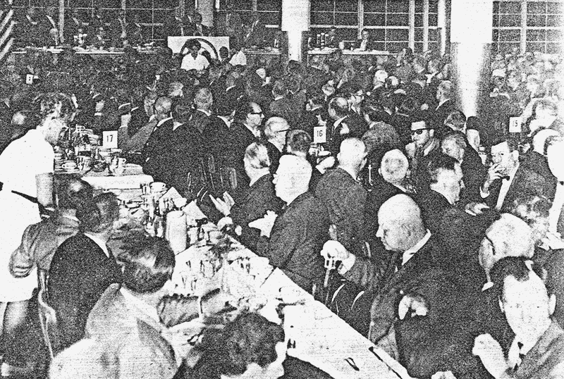 long tables, packed room, men only, in suits and tuxes