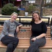 Former Society President Kate Jiggins and former Vice President Erin Betley sit on a commemorative bench at the Cynwyd Station.